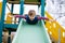 Happy blond kid boy having fun and sliding on outdoor playground. Funny joyful child smiling and climbing on slide