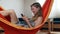 Happy blond laughing girl in hammock using her cellphone