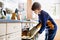 Happy blond school kid boy baking blueberry vanilla muffins in domestic kitchen, indoors. Funny lovely healthy child