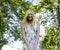 Happy blond young woman in park smiling, floral close up