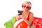 Happy blonde caucasian female stands in swimsuit with big rubber mattress, phone, earphones, do selfie and smiles