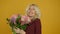 Happy blonde girl accepting flower bouquet and laughing at camera