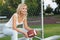 Happy blonde girl with american football. Smiling cheerful beautiful young woman sitting on the bench. Outdoors. Fan of football