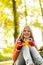 Happy blonde girl teen sitting forest fall