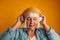 Happy blonde hair 50s woman dancing to the rhythm of the melody, listening to the song in wireless headphones