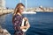 Happy blonde mediterranean woman embracing hat at Malta