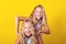 Happy blonde sisters twins having fun together. Family, childhood, teens and relationship concept. Summer fashion, teen cosmetic,