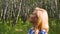 Happy blonde woman walking in city park and enjoying summer day. Profile view