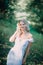 Happy blonde woman in white summer dress walks in park. Fashion