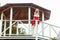 Happy blonde young woman in stylish red white dress posing in wooden garden arbor. standing and looking at camera with toothy