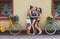 Happy boho chic girls pose with bicycles near house facade