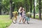 Happy boho chic girls ride together on bicycles in park