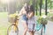 Happy boho chic girls ride together on bicycles in park