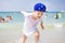 Happy boy bathing. little boy runs along seashore against background of people swimming in sea