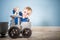 Happy boy blond in a blue sweater sits on a wooden floor. One year old baby playing with wooden toys. Cat and train made of wood