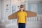 Happy boy with cardboard boxes of wings in home dream of flying