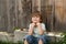 Happy boy. A child with a smile. Kid sits near a wooden fence. Happy summer. August or September.