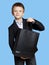 Happy boy in the clothing business holds purchase in a black plastic bag isolated on blue background