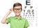 Happy boy in eyeglasses over eye chart