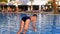 Happy Boy in Flippers Jumping into the Blue Water Pool. Slow Motion