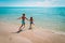 Happy boy and girl run to swim on beach