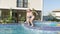 happy boy and girl running and jumping in swimming pool, children having fun, splashing water. Summer travel family