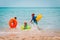 Happy boy and girls with floaties run swim on beach