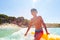 Happy boy playing in waves with inflatable float