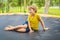 Happy boy plays outdoors in garden jumping high in the sky on trampoline