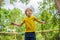 Happy boy plays outdoors in garden jumping high in the sky on trampoline