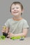 A happy boy plays, repairs and collects his toy machine from details using a screwdriver. Vertical photo, looking at the camera