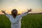 Happy boy with raised hands looks at the sunset  in summer. Boy in a field with his hands raised while sunrise. Freedom and