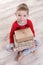 Happy boy in red pajamas with Christmas gifts. Kraft packaging.