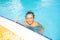 Happy boy resting at the edge of swimming pool