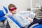 A happy boy in safety glasses with dental X-rays radiographs in her hands sitting in a dentist office