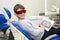 A happy boy in safety glasses with dental X-rays radiographs in her hands sitting in a dentist office