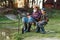 Happy boy sitting on chairs together with his experienced old grey-bearded granddad and fishing with rods on the lake.