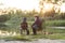 Happy boy sitting on chairs together with his experienced old grey-bearded grandpa and fishing with rods on the lake.