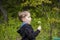 A happy boy on a spring day in the garden blows on white dandelions, fluff flies off him. The concept of outdoor recreation in