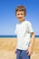 Happy boy standing on the summer beach. Young teenager relax and having fun in summer holiday vacation travel.