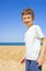 Happy boy standing on the summer beach. Young teenager relax and having fun in summer holiday vacation travel.