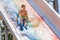 A happy boy on water slide in a swimming pool having fun during summer vacation in a beautiful aqua park. A boy