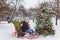 Happy boys sledding near christmas tree in winter day outdoor