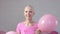 Happy breast cancer survivor woman appears out of pink ballons smiling and looking into the camera - breast cancer