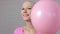 Happy breast cancer survivor woman appears out of pink ballons smiling and looking into the camera - breast cancer