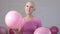 Happy breast cancer survivor woman smiling looking at the camera and playing with pink ballons - breast cancer awareness