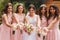 Happy bride with bridesmaid hold bouquets and have fun outside. Beautiful bridesmaid in same dresses stand by the