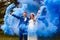 Happy bride and groom with blue smoke bombs