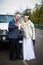 Happy bride and groom near wedding limo