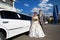 Happy bride and groom near wedding limo